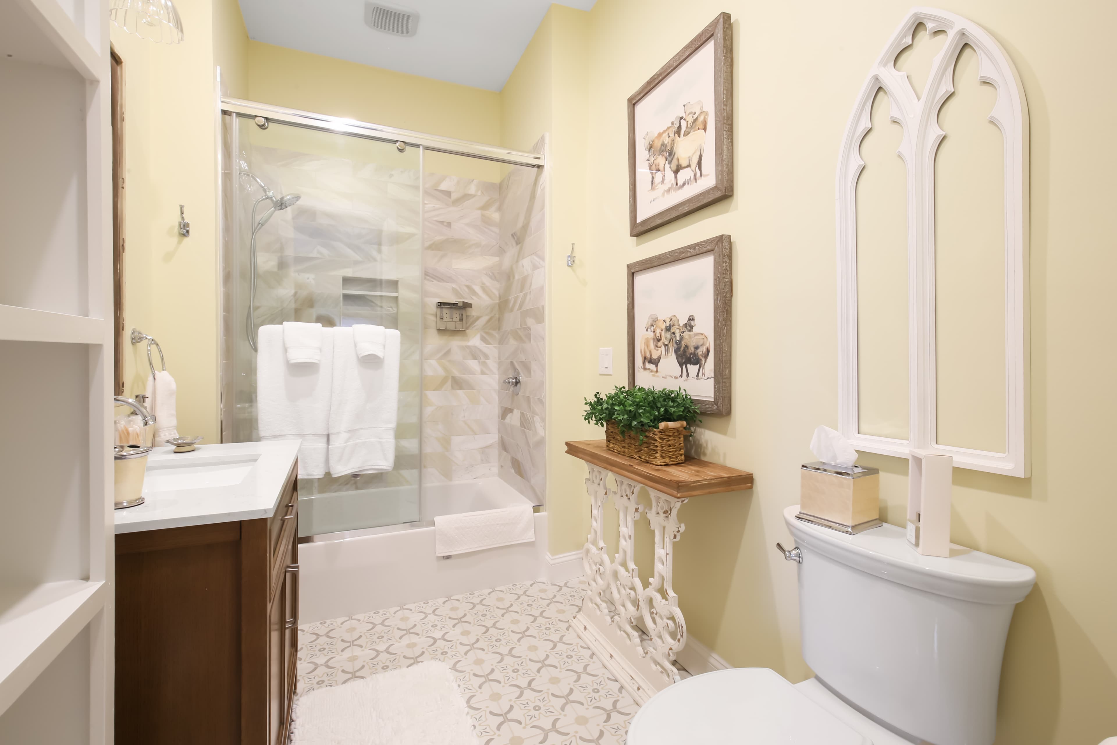 A modern bathroom featuring a glass shower, decorative artwork, and light yellow walls.