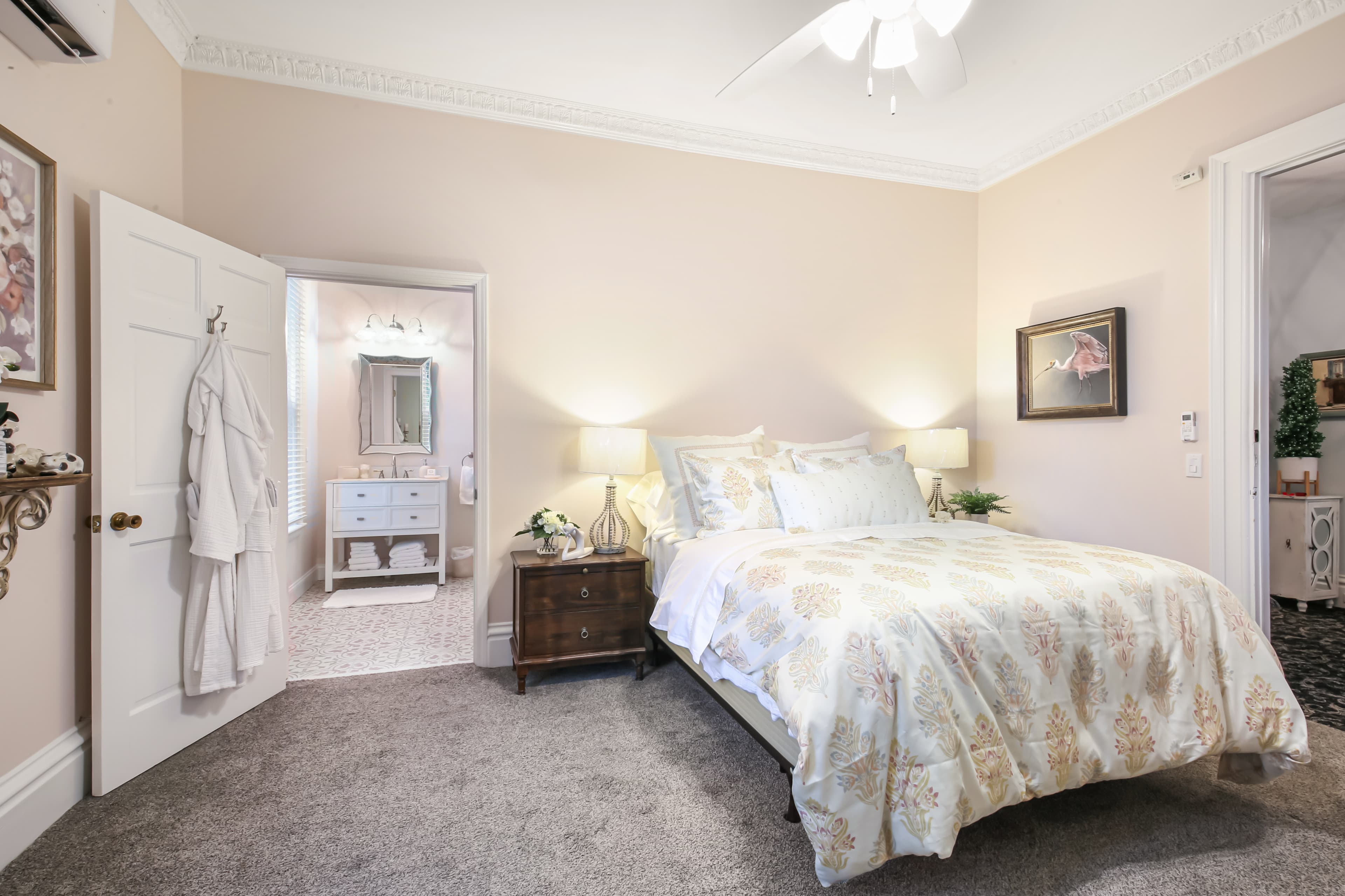 Cozy bedroom featuring a bed with decorative bedding, two lamps, and an adjoining bathroom entrance.