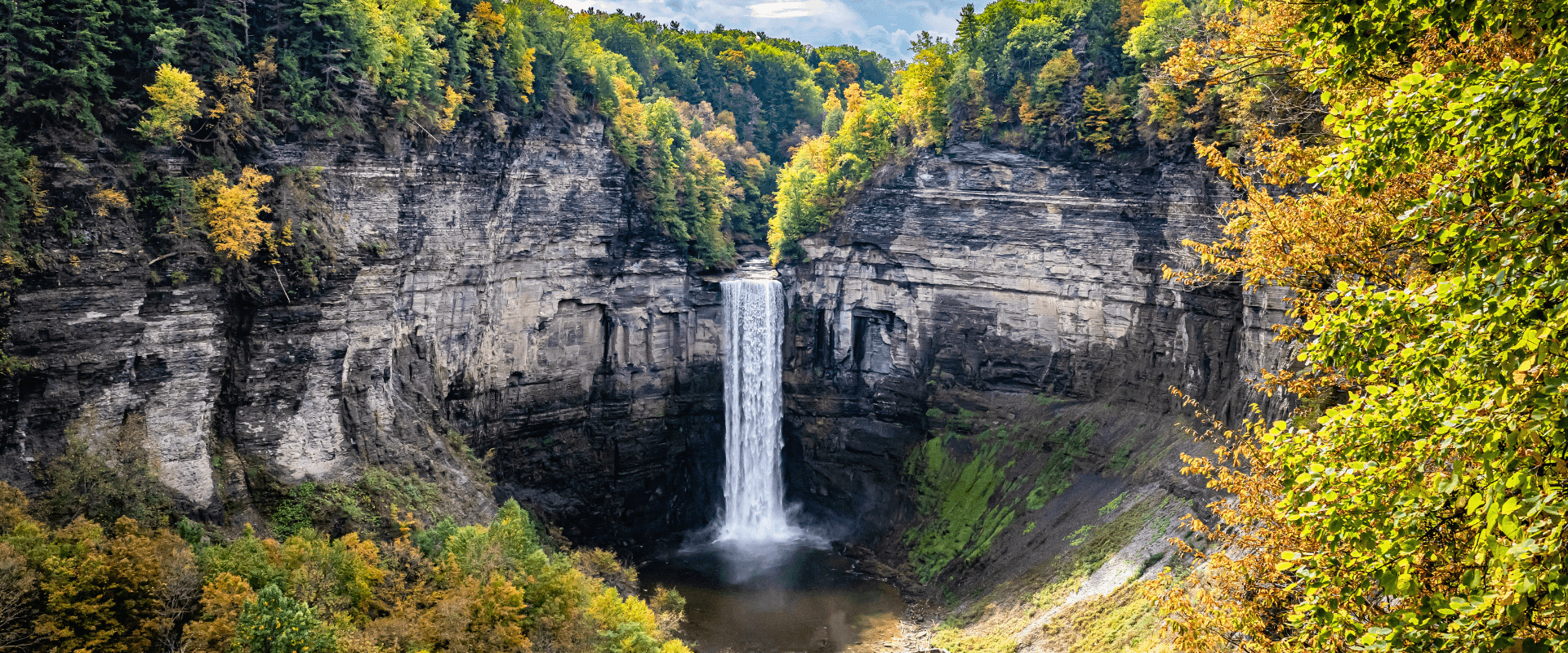 A cascading waterfall surrounded by vibrant autumn foliage in a rocky canyon.