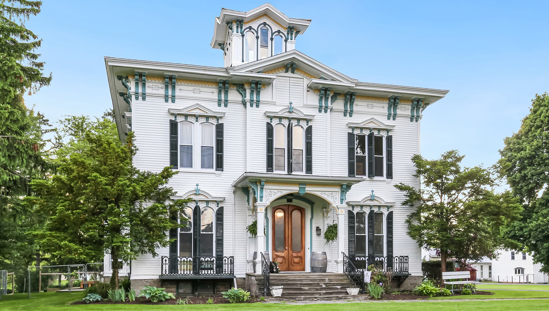 A large, ornate white Victorian house with decorative trim and a distinct tower.