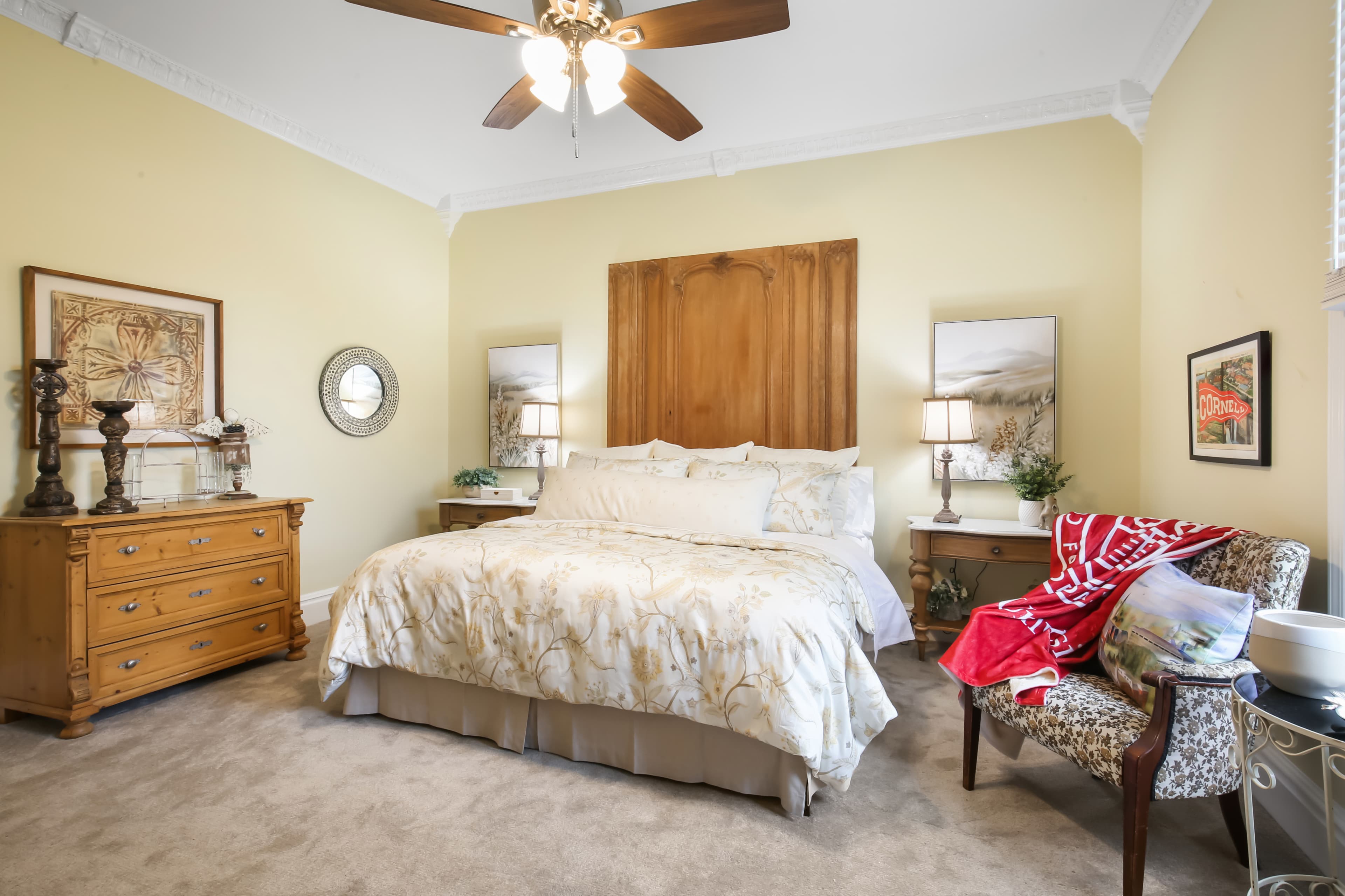 Cozy bedroom featuring a queen-sized bed, wooden dresser, and comfortable seating.