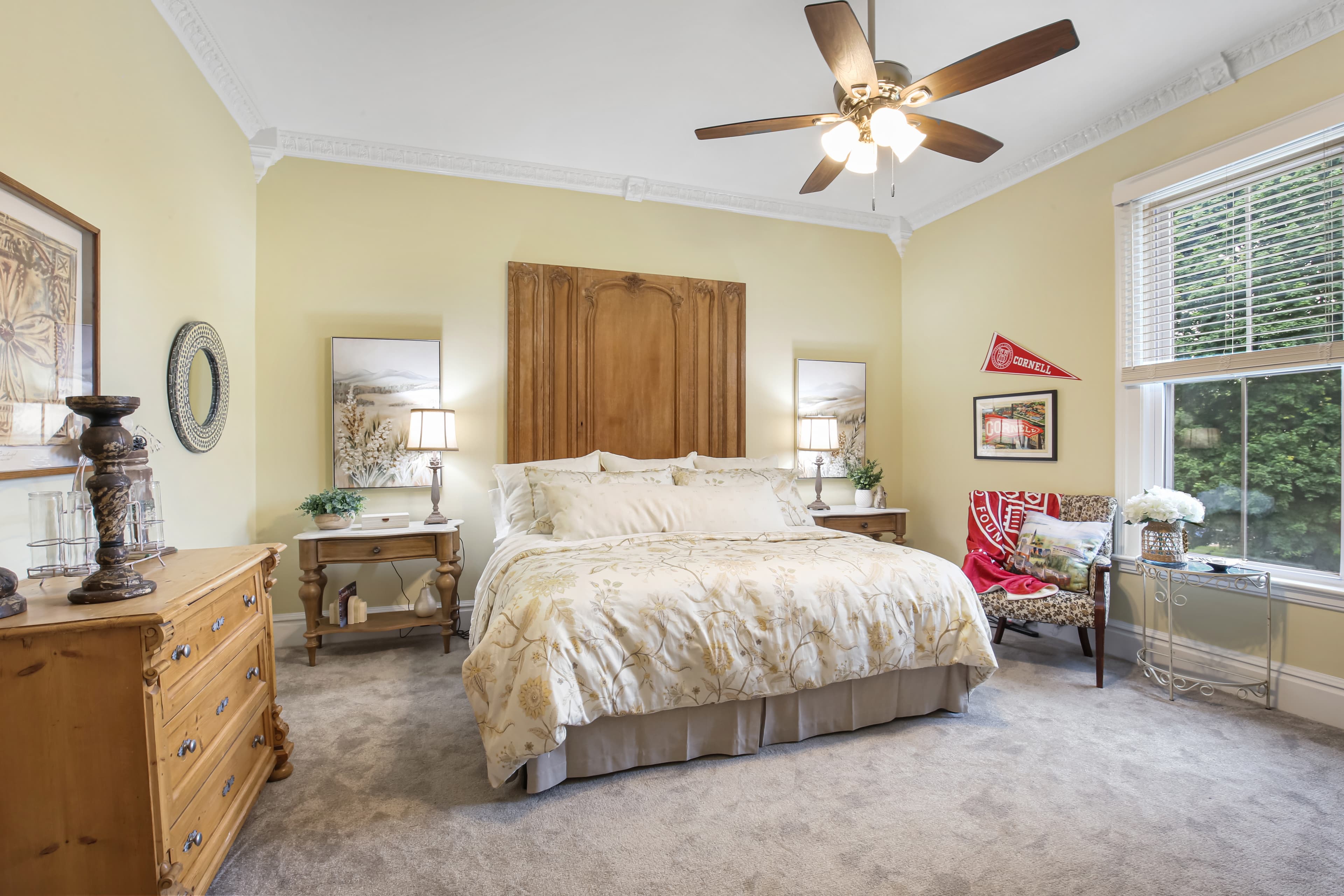 A cozy bedroom featuring a large bed, wooden furniture, and decorative elements in warm colors.
