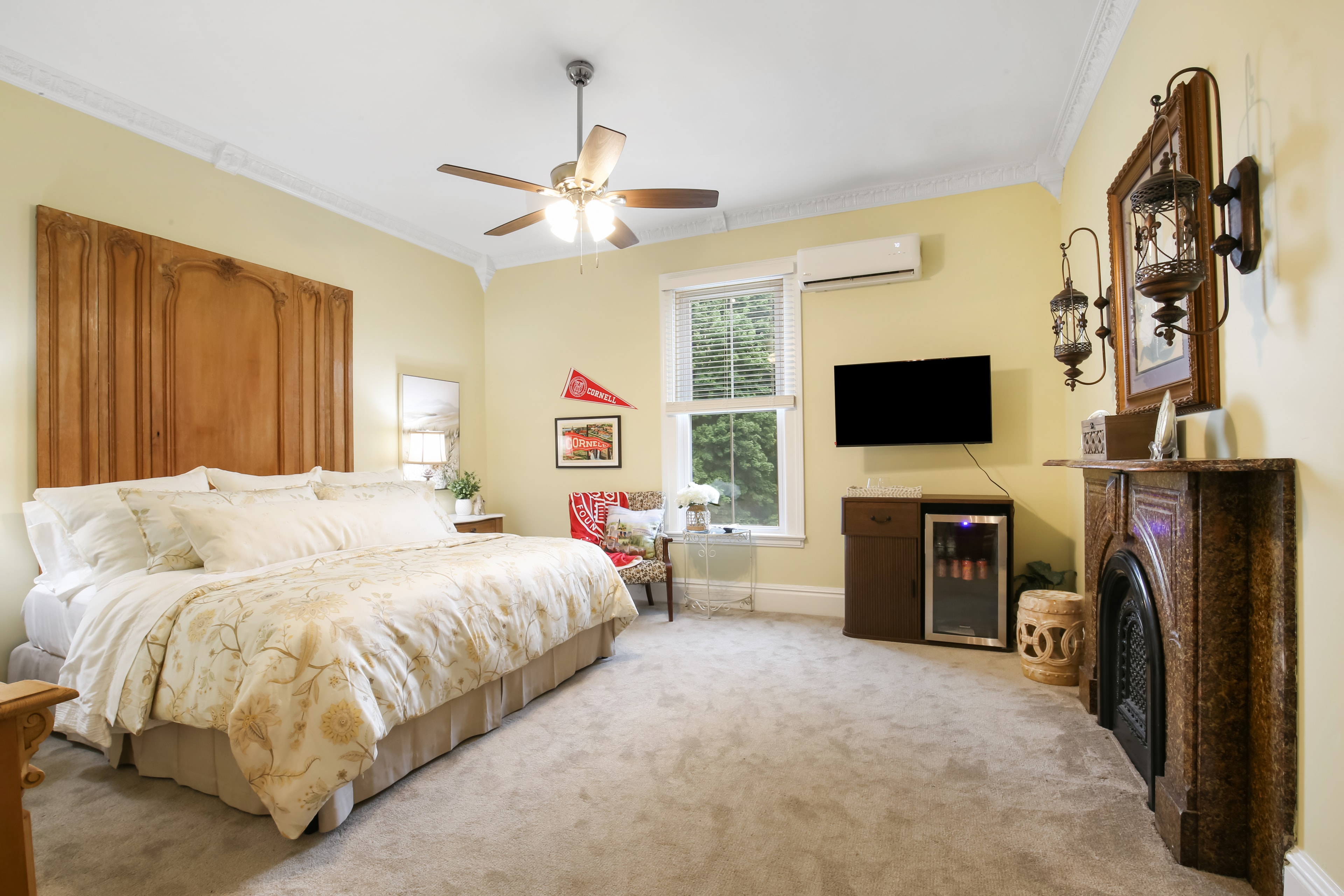 A spacious, softly lit bedroom with a king-size bed, wall-mounted TV, and vintage decor.