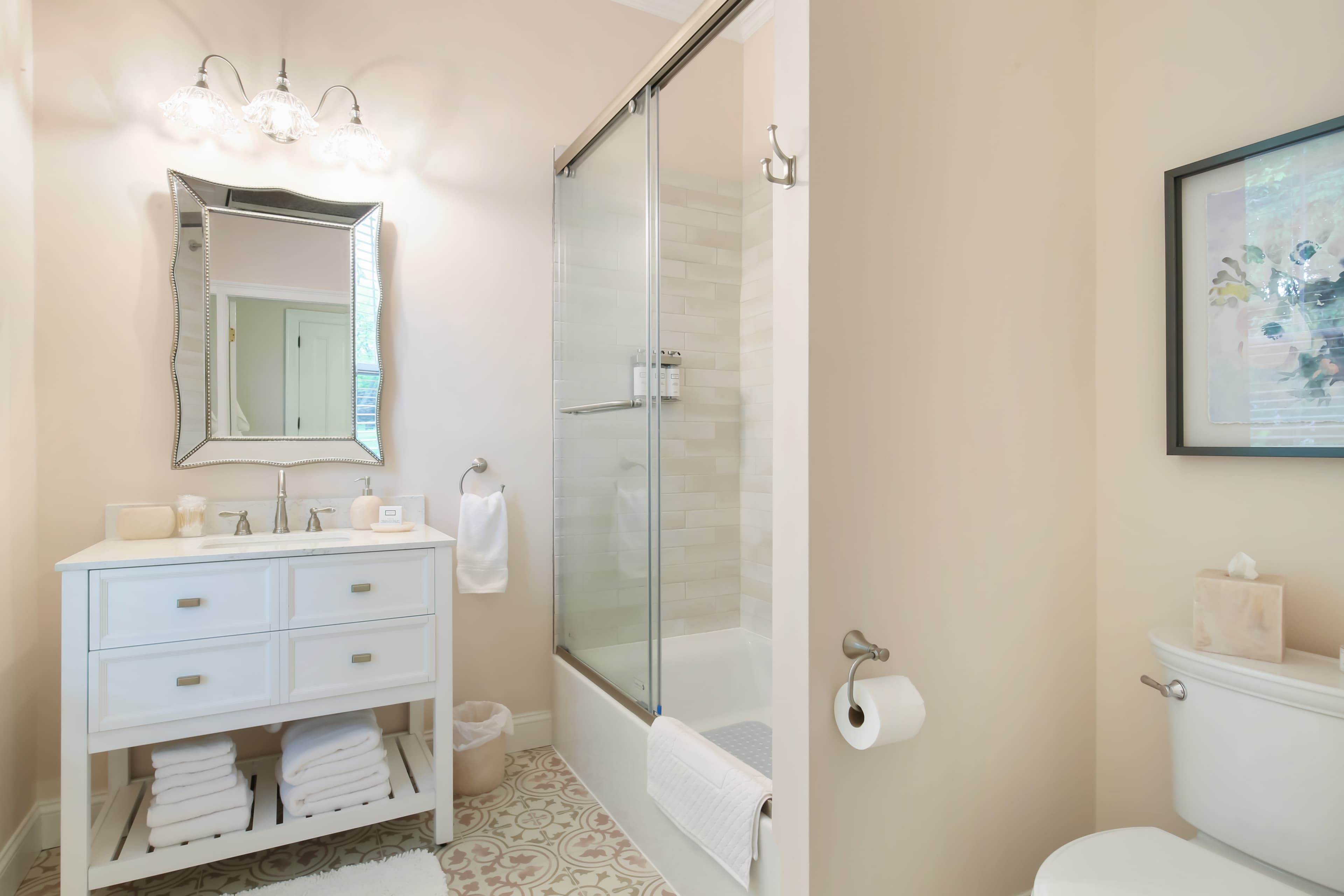 Bright and modern bathroom featuring a glass shower, white vanity, and neatly stacked towels.