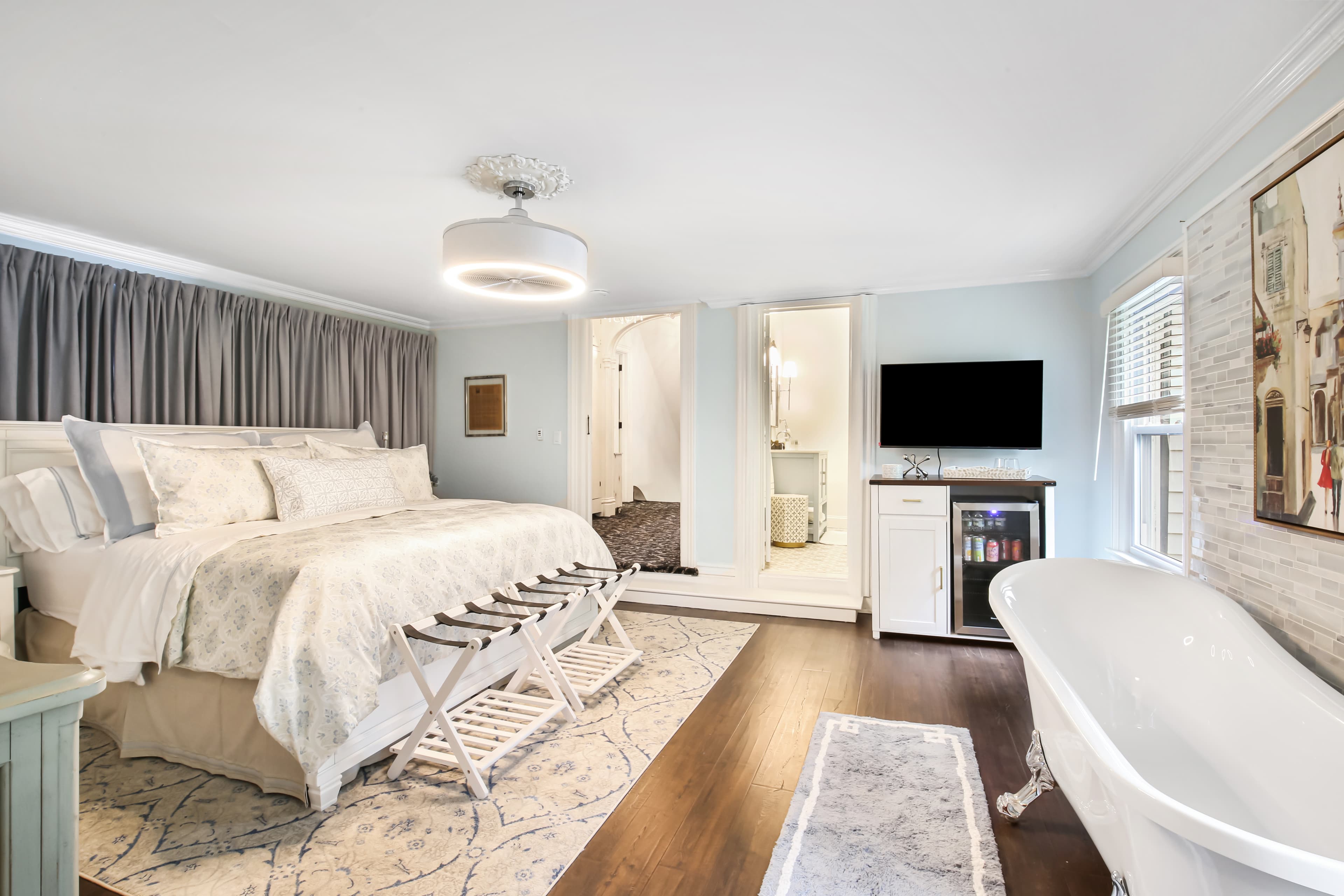 A stylish bedroom featuring a king-sized bed, a freestanding bathtub, and modern decor.
