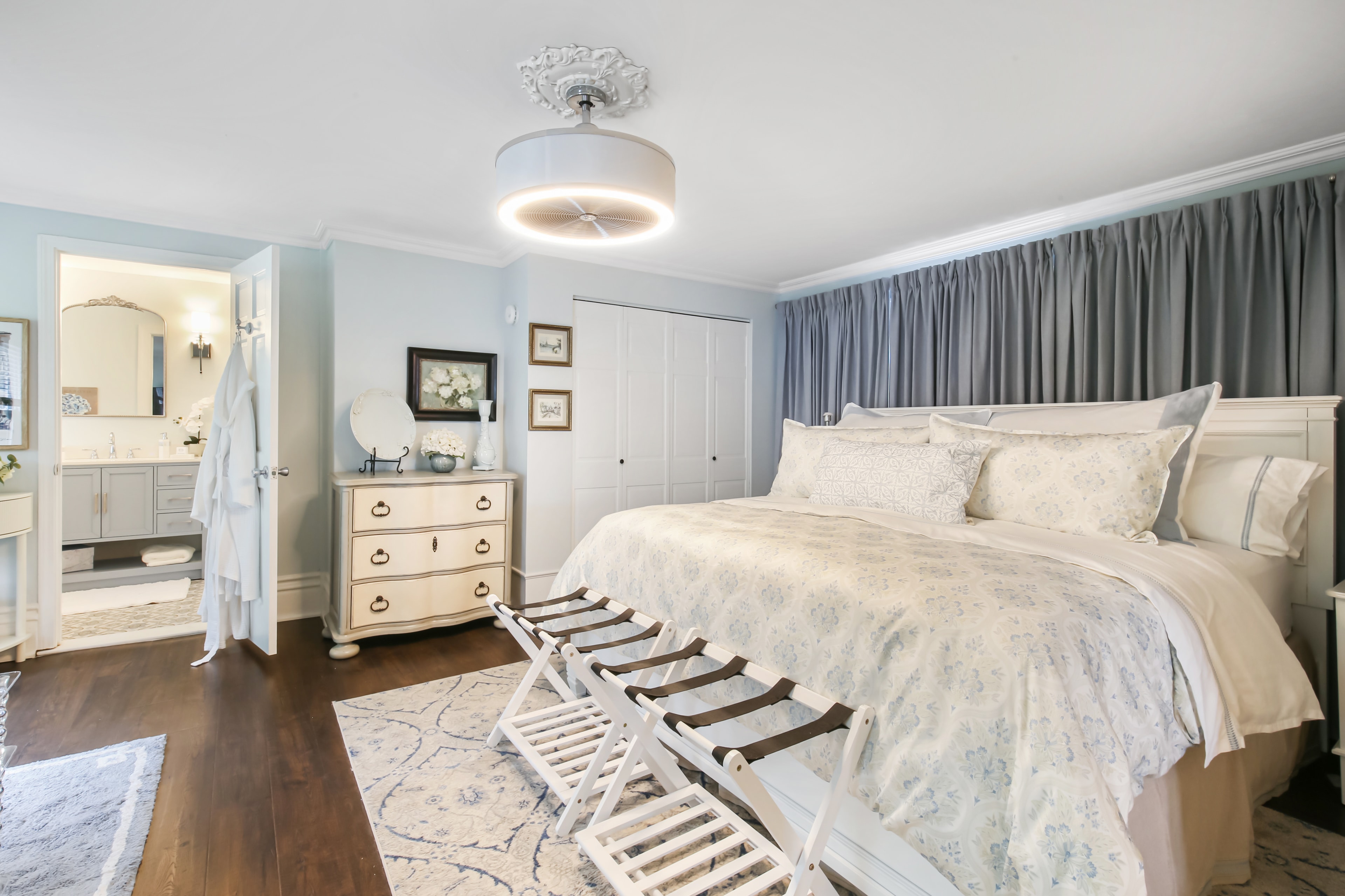 A cozy, well-decorated bedroom featuring a large bed, nightstands, and light blue walls.