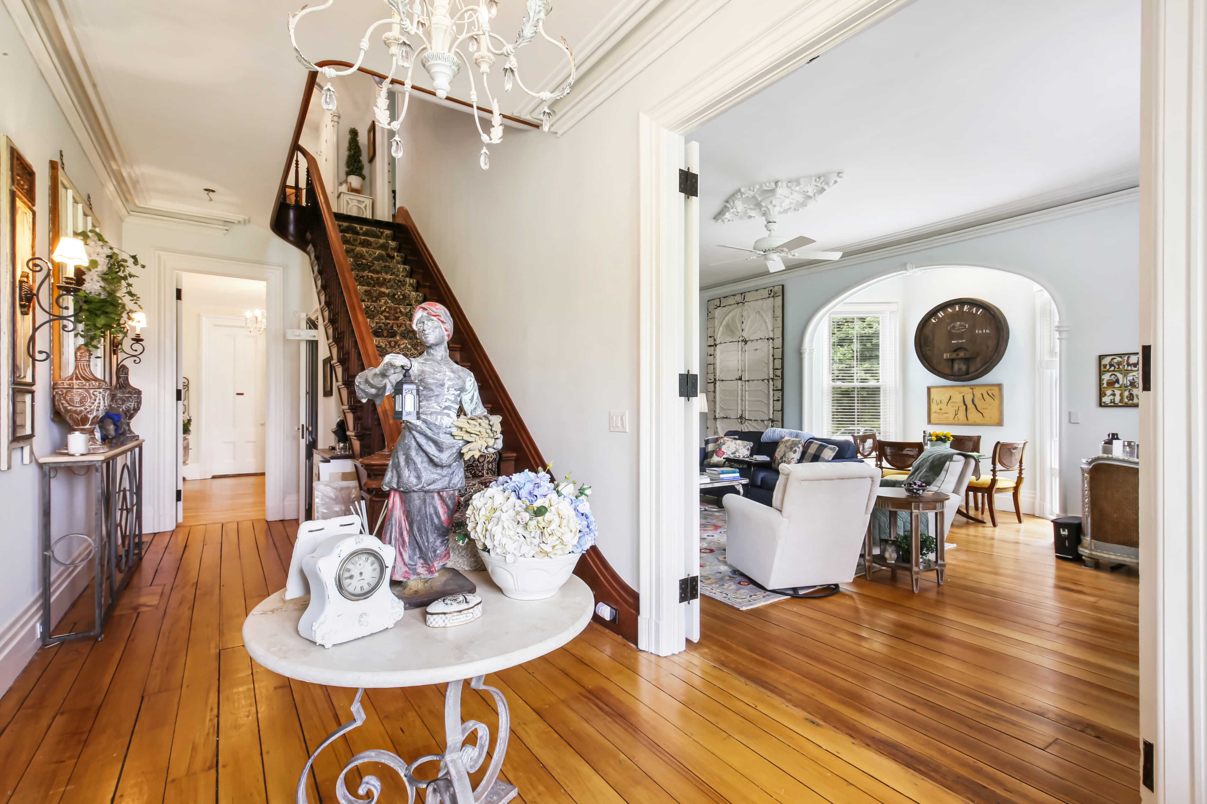 A stylish foyer with a chandelier, decorative table, and staircase leading to a living area.